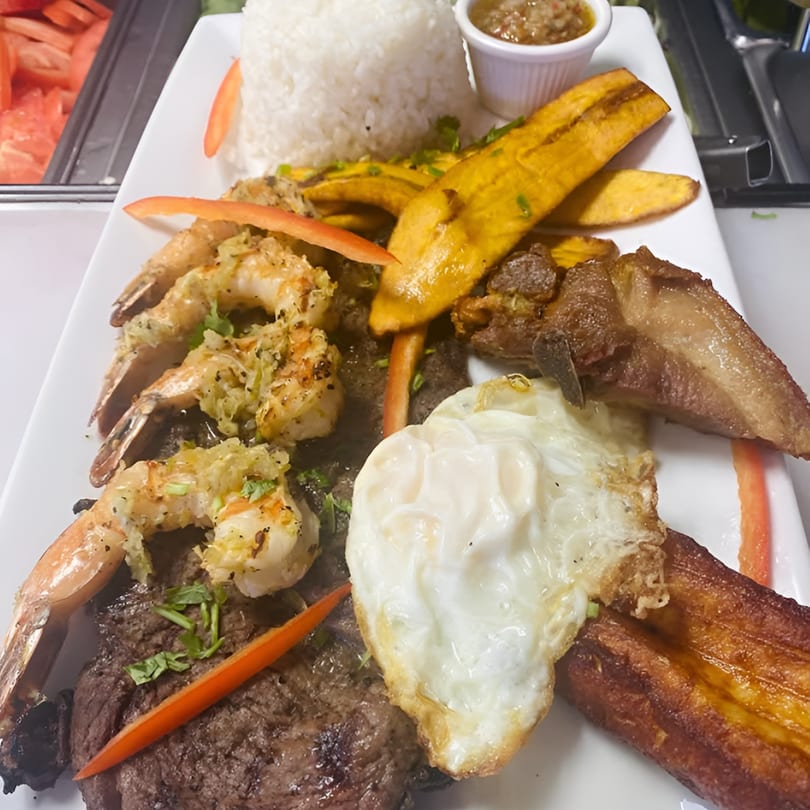 A Latin-American platter with steak, shrimp, fried egg, plantains, rice, and pork belly.