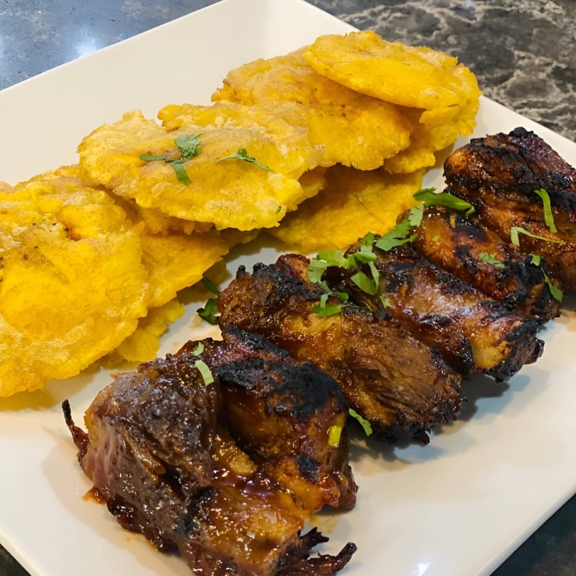 Parrilla Latina's grilled ribs with a side of crispy fried plantains, garnished with fresh cilantro.