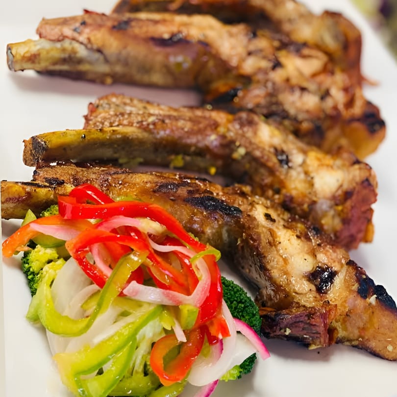 Grilled ribs with a side of fresh broccoli, red and green bell peppers, and sliced onions.